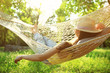 Leinwandbild Motiv Young woman with hat resting in comfortable hammock at green garden