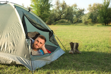 Canvas Print - Young man lying inside camping tent on sunny day