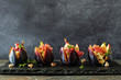 © Jenifoto - Fig appetizers with blue cheese, prosciutto and honey. Side view in a row on a dark state serving board.