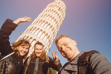 Wall Mural - Group of friends makes selfie photos against background falling tower in city of Pisa, Italy. Travel concept