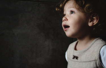 beautiful young girl looking away against a dark moody background