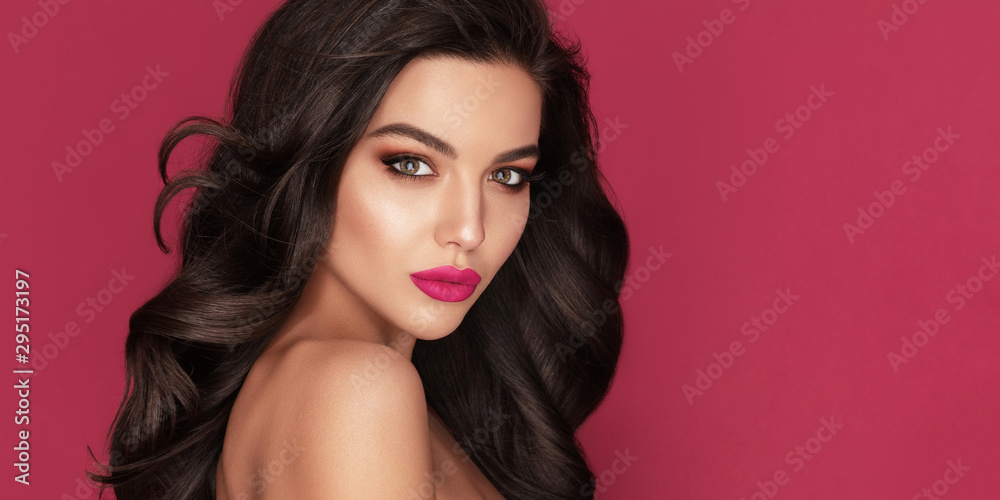 Beauty Fashion Woman Brunette Portrait with brown eyes and Healthy Long Shiny Wavy black hair. Volume shampoo. Attractive model with professional make up against red background - obrazy, fototapety, plakaty 