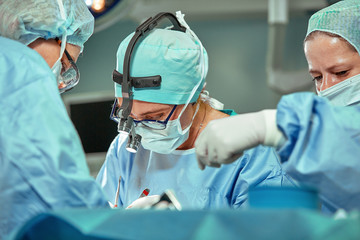 Wall Mural - Group of surgeons looking at patient on operation table during their work