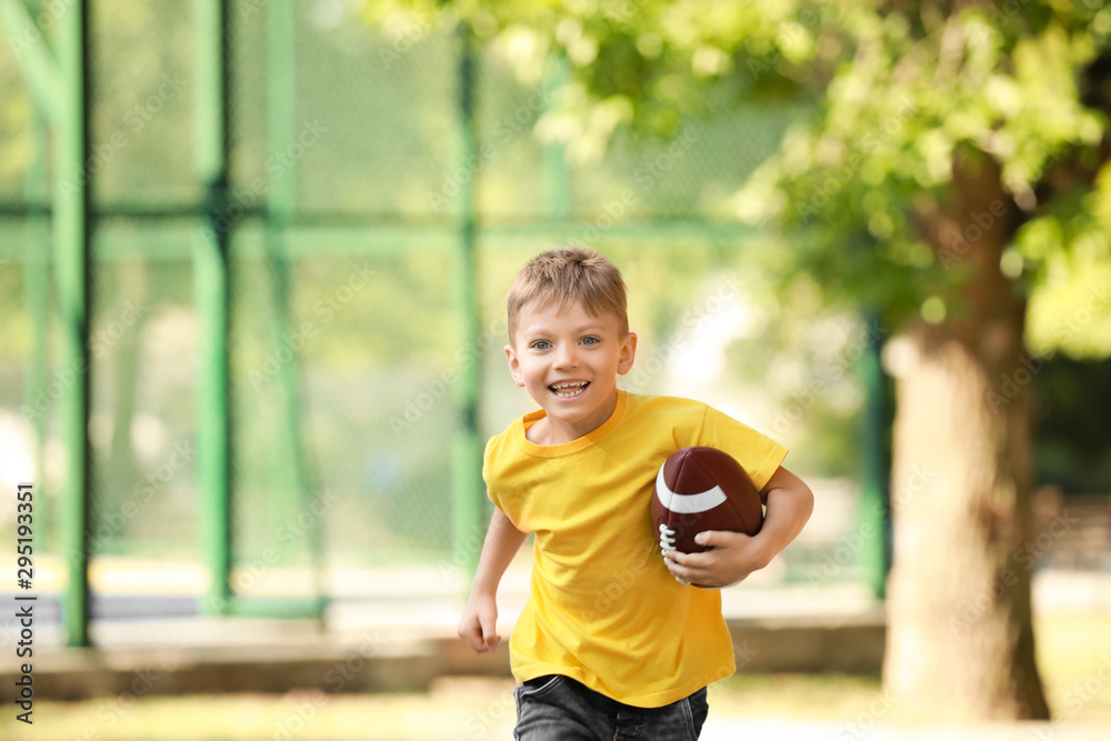 Running little boy with rugby ball in park