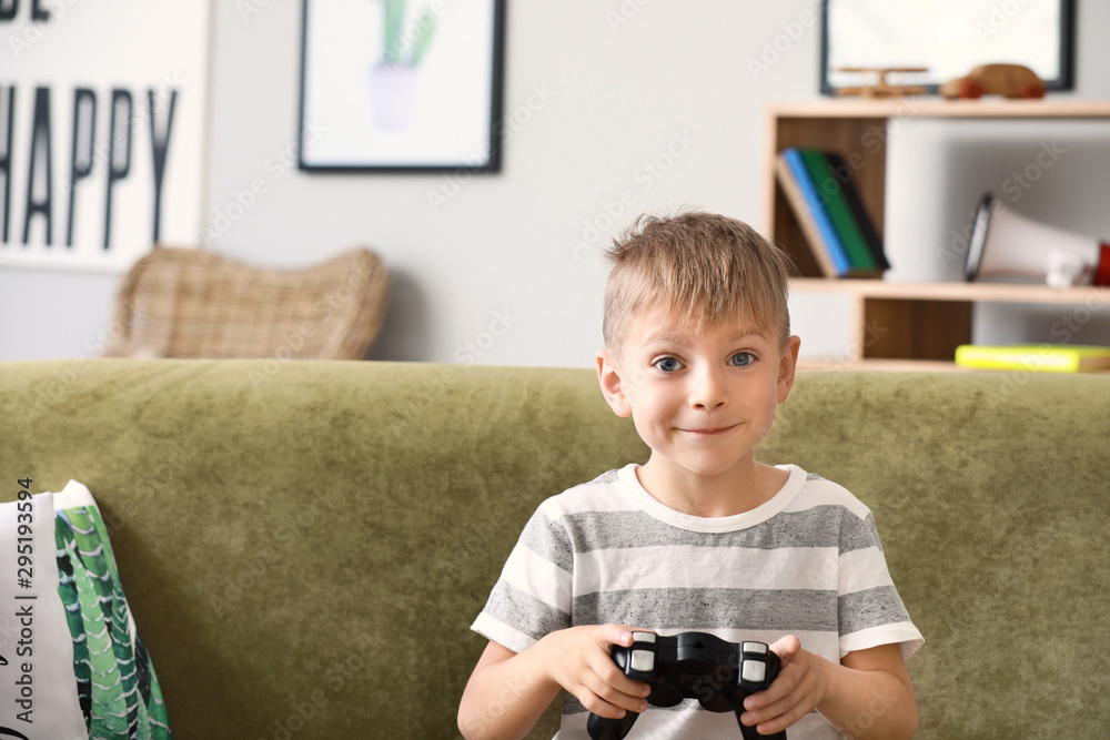 Cute little boy playing video games at home