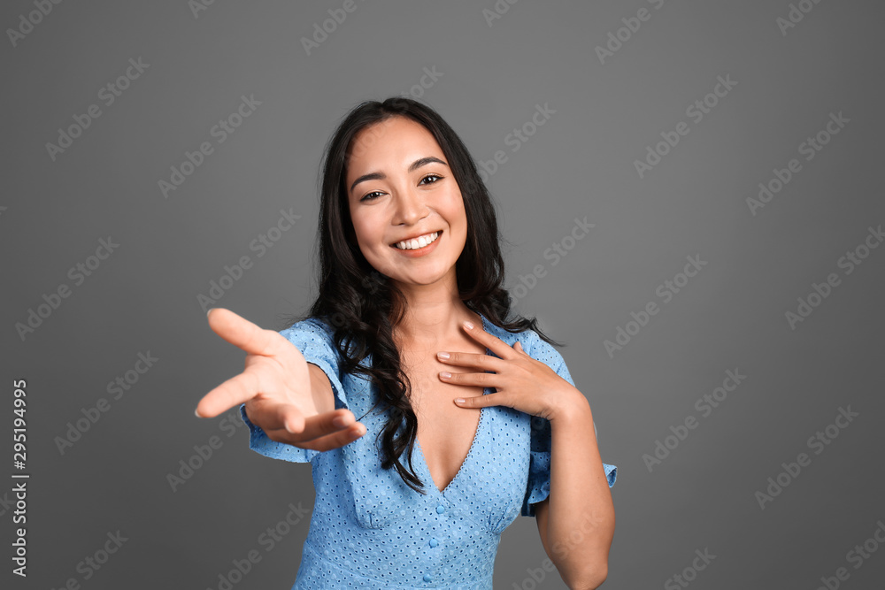 Beautiful Asian woman inviting viewer on grey background