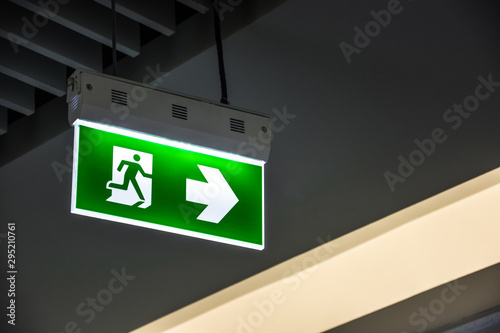 Fotografía Illuminated green emergency exit sign hanging on ceiling in modern building