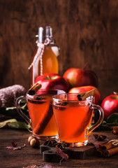 Hot mulled apple cider with with cinnamon sticks, cloves and anise on wooden background. Traditional autumn, winter drinks and cocktails