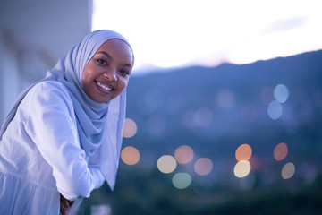 African  modern Muslim woman in night at balcony