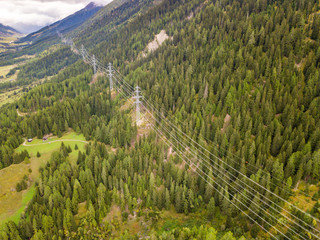 Wall Mural - Aerial view of power line and pylon in alpine valley of Goms in Switzerland. Power grid through alps. 