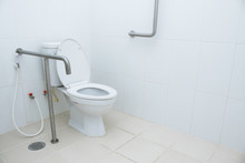 Restroom Interior For Elderly Senior People Or Handicapped With Lavatory Toilet Bowl And Stainless Steel Handrail. Disability Toilet With Handle Bar In A Public Convenience Area. 