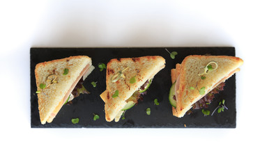 triangle club sandwich tripple set on black ceramic plate against white background