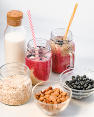 Berry smoothie in two glass jars with straws. Healthy breakfast - milk in a glass jar, oatmeal, almonds and blackberries. The concept of healthy eating and dieting.