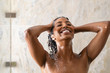 African woman washing hair under shower