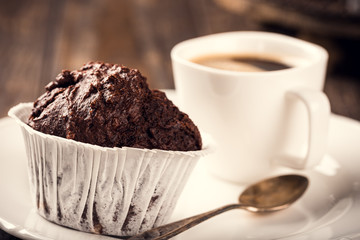 Wall Mural - Chocolate muffins with banana in white paper cups on dark wooden background. Party food concept.