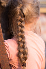 Pigtail of hair at the girl. Women's hair close-up.