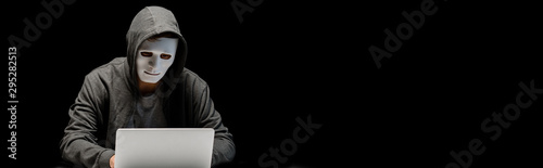 Fotomural panoramic shot of anonymous internet troll in mask typing on laptop keyboard iso