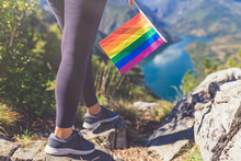 Female Standing Of Top Of The Mountain And Holding Rainbow Pride Gay Flag.