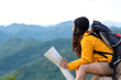 © freebird7977 - Asian women hiker or traveler with backpack adventure holding map to find directions and sitting relax on the mountain nature for destination leisure trips. Travel and Lifestyle Concept