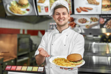 Delicious Hamburger And Fried Potatoes In Hands Of Male Cook