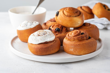 Delicious Cinnamon Rolls with cheese cream on a white plate. Copy space.