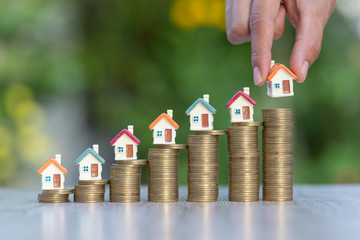 House on a coin ladder.Model house on coins The hand is going to put the house on the coin.Real estate concept,mortgage and investment.Saving money or investing for future homes.space to enter text