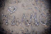 Overhead Shot Of Sand On Beach With Stones Spelling "Ti Amo" Which Means "I Love You" In Italian