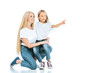 © LIGHTFIELD STUDIOS - happy mother sitting near daughter pointing with finger on white