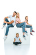 © LIGHTFIELD STUDIOS - happy family sitting on cube and looking at camera on white