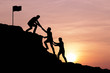 © cofficevit - Silhouette of people helping each other hike up a mountain at sunset background. Teamwork, success and goal concept.