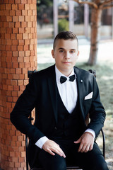 Portrait of a handsome young businessman siting on the terrace of a coffee shop. Handsome young guy in suit.