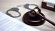 Handcuffs on table, gavel lying on sound block, crime punishment, law order