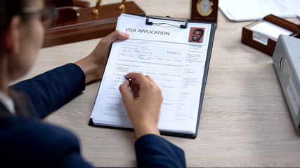 Female embassy worker checking visa application office, immigration regulation