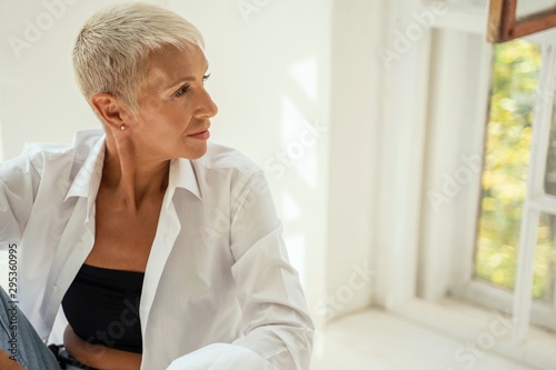 Cuadros en Lienzo Attractive blonde woman looking at the window
