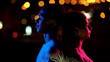 © motortion - Boy illuminated by blue, girl in pink light at night, concept of man vs woman