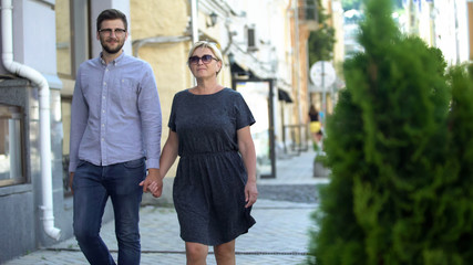 Mature woman walking on street with younger men, relations and connection