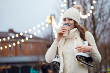 Charming young woman in the Park near the ice rink. Smiling brunette with skates