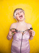 stupid person cuts electric wire with scissors. silly blonde in pink dress plays bad with electricity on yellow studio background