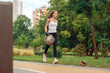 © Viktoriia - Plogging. Young girl volunteer in gloves running outdoors picking up litter smiling pensive