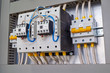 © AndreiNN - Two powerful electrical contactors or magnetic starters and two circuit breakers in the electrical Cabinet. Power cables and wires are connected to contactors and circuit breakers. Side view.