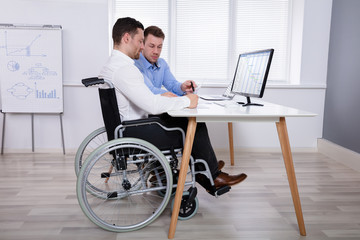 Two Colleagues Working On Computer In Office