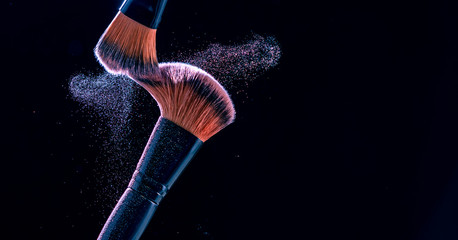 Make up brush with  powder explosion on black background