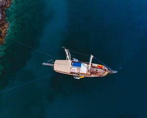 Wall Mural - Top down drone shot of a traditional Turkish gulet in the dark blue Mediterranean sea. 