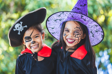 two asian child girls in halloween costumes and makeup having fun on halloween celebration