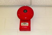 A Red Fire Alarm Hanging On A White Brick Wall