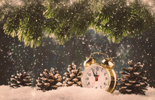 Christmas Or New Year Background With Golden Alarm Clock In Snowdrifts On Blue Background With Pine Cones, Fir Tree, Holiday Lights Counting Last Moments Before Christmass Countdown To Midnight