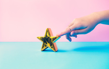 Wall Mural - customer review concepts with female finger and gold star on pastel color background