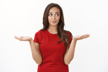Waist-up Shot Cute Silly Brunette Female In Red Casual T-shirt, Shrugging Raising Hands Up Questioned, Smirk And Look Away Making Choice, Pondering Between Variants, Standing White Background