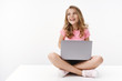 © Cookie Studio - Carefree cheerful blond caucasian cute kid young sister sitting floor with laptop, laughing joyfully, studying online, digital education, look away left copyspace, smiling happy, learn new language