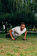 © qunica.com - Push ups or press ups exercise by young man while working out on grass crossfit strength training
